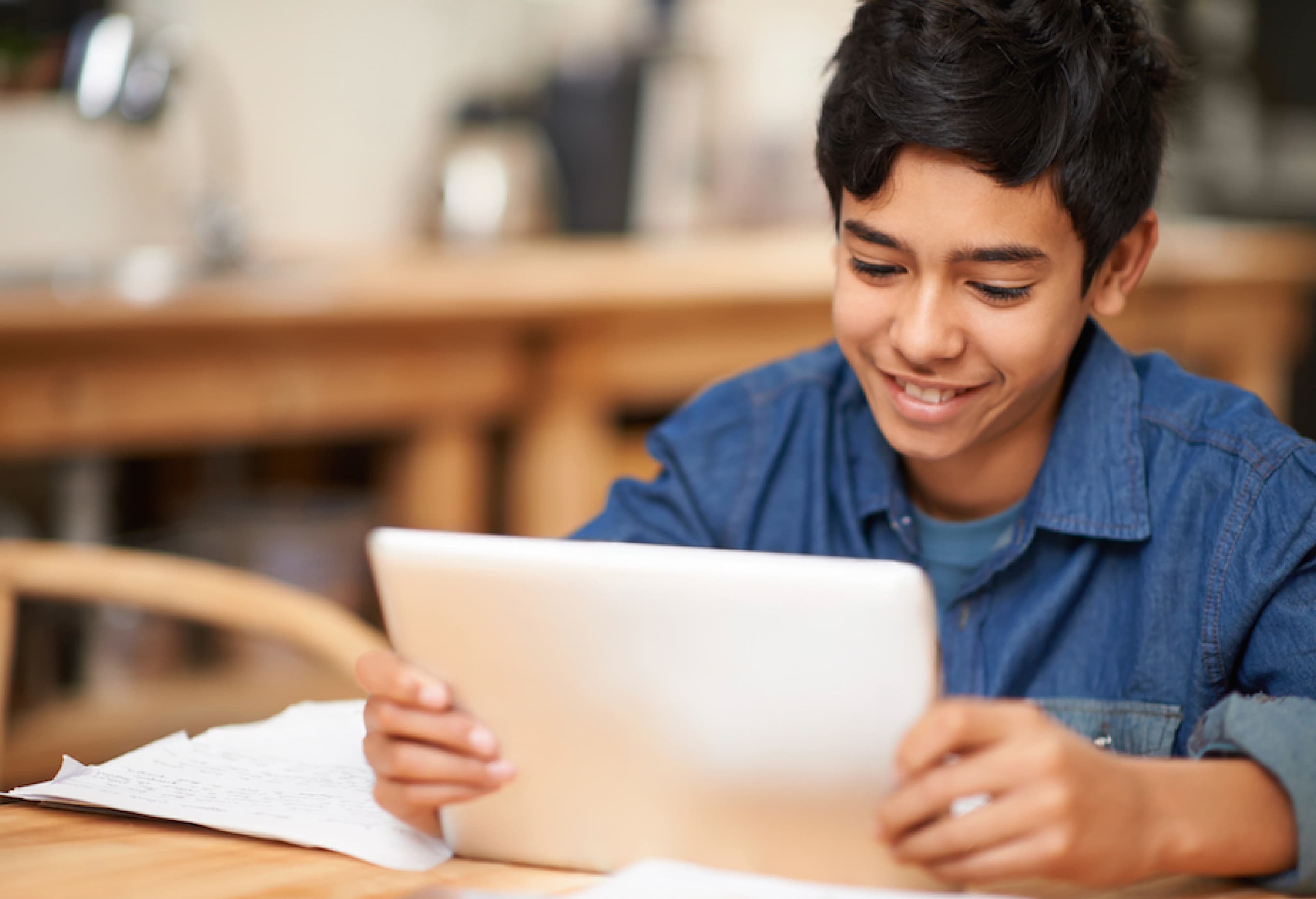 Smiling student using a tablet at a desk