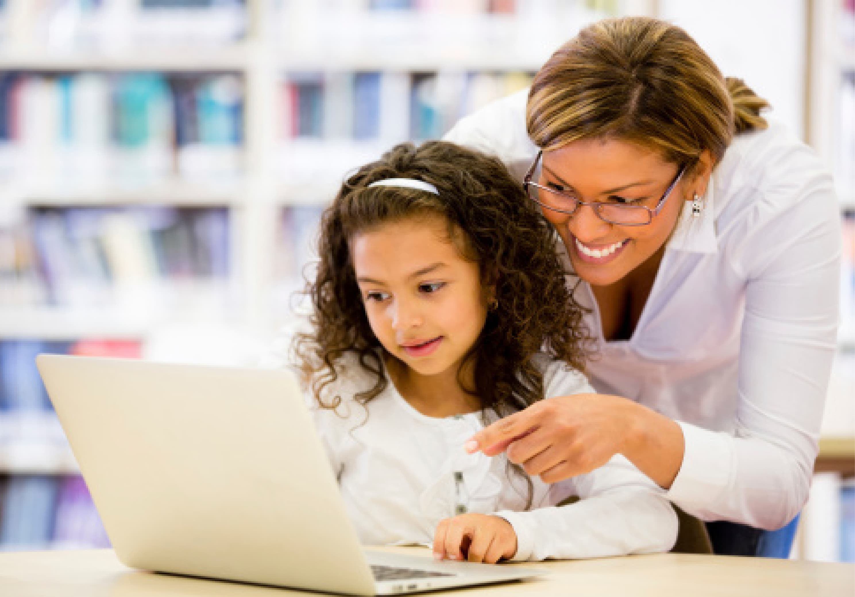 Teacher helping a young girl working on a laptop