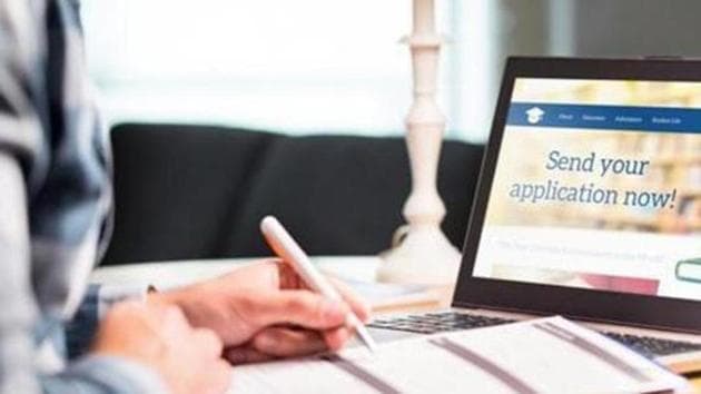 Person filling a form beside a laptop showing an online application page