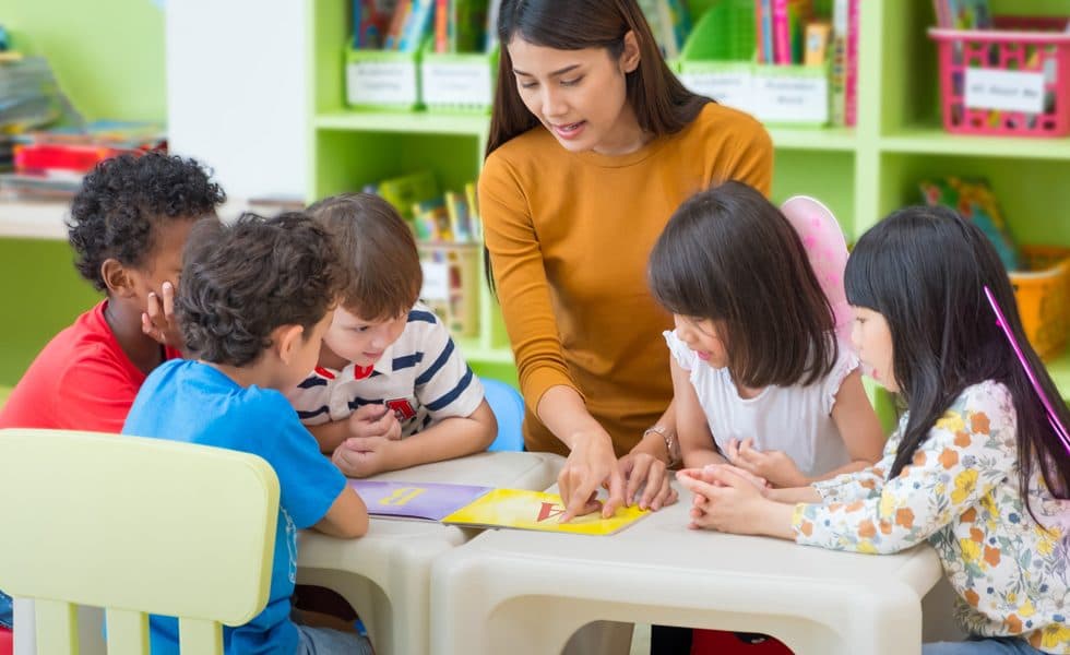Teacher reading a picture book with young children at a table