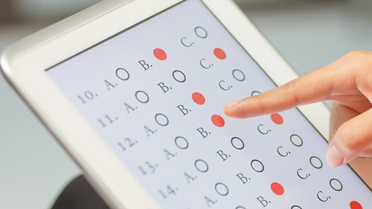 Finger selecting answers on a multiple-choice test on a tablet