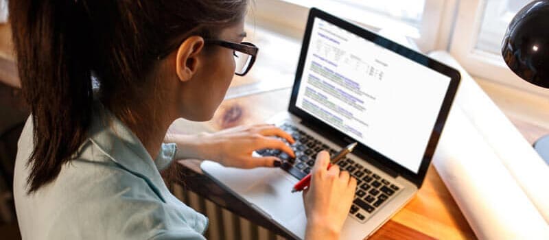 Teacher typing a report on a laptop